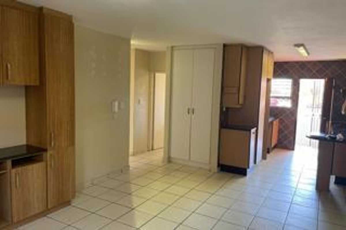 A functional kitchen area featuring built-in cabinetry, tiled flooring, and a dedicated pantry cupboard, offering a clean and versatile space for renovation.