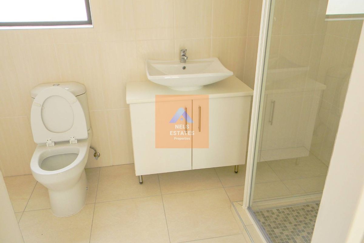 A modern bathroom featuring a vessel sink vanity, a white ceramic toilet, and a glass-enclosed shower with tiled flooring.