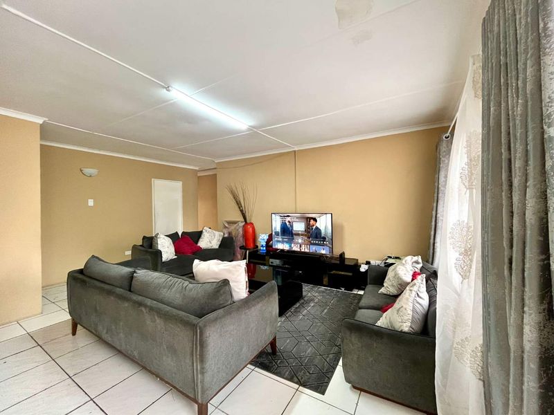 A living room featuring tiled flooring and ceiling lighting, showing visible signs of ceiling water damage and wear.