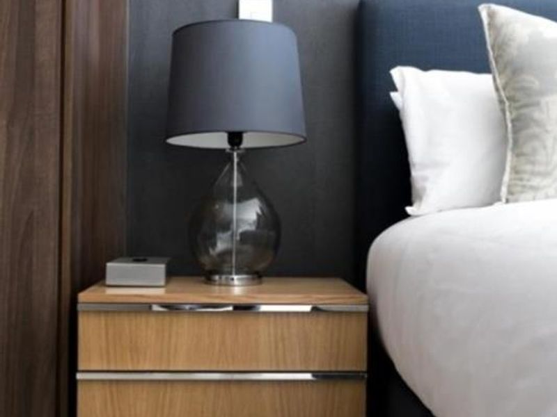A modern bedroom featuring a built-in wardrobe with dark wood finish and a window fitted with venetian blinds.