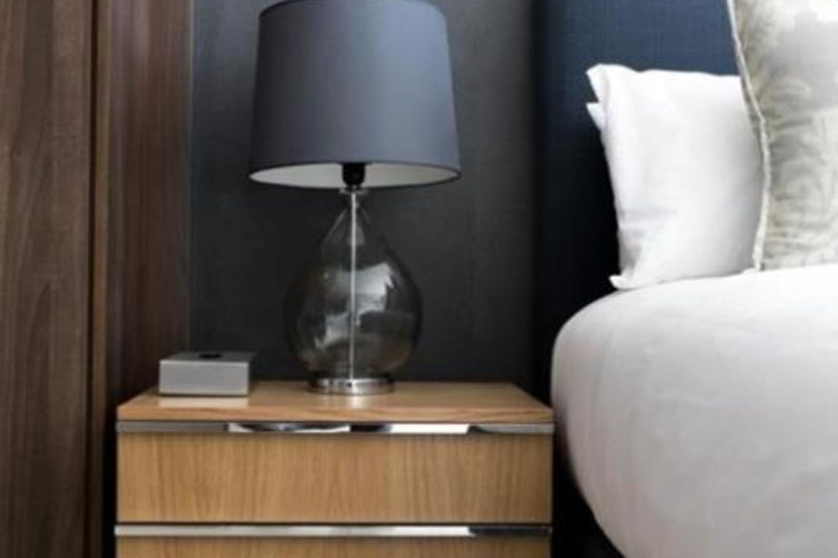A modern bedroom featuring a built-in wardrobe with dark wood finish and a window fitted with venetian blinds.