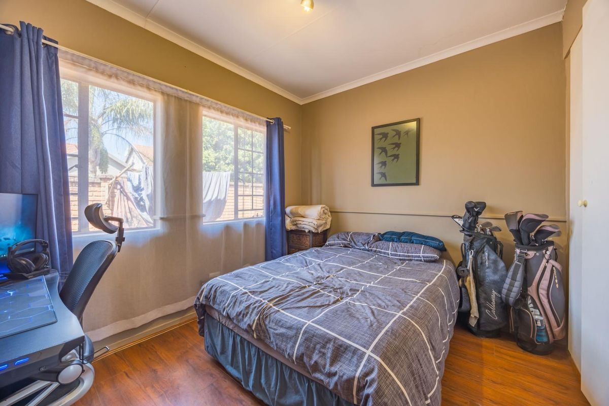 A functional bedroom featuring laminate flooring, built-in storage, and large windows that provide natural light.