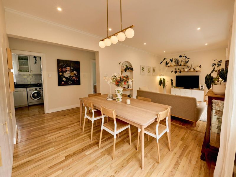 Spacious open-plan living and dining area featuring warm hardwood flooring, recessed lighting, and a seamless transition to the adjacent kitchen space.