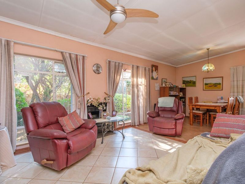 Open plan living and dining area featuring tiled flooring, a ceiling fan, and sliding glass doors providing access to the garden.