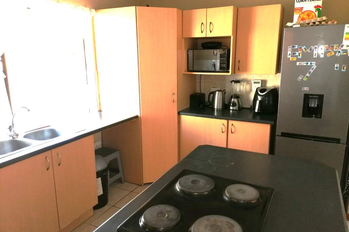 Functional kitchen featuring light wood-tone cabinetry, dark laminate countertops, a built-in electric hob, and a double basin sink.