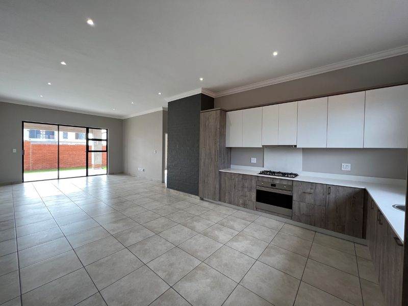 Spacious open-plan kitchen and living area featuring modern cabinetry, built-in appliances, tiled flooring, and large sliding doors leading to the outdoor space.