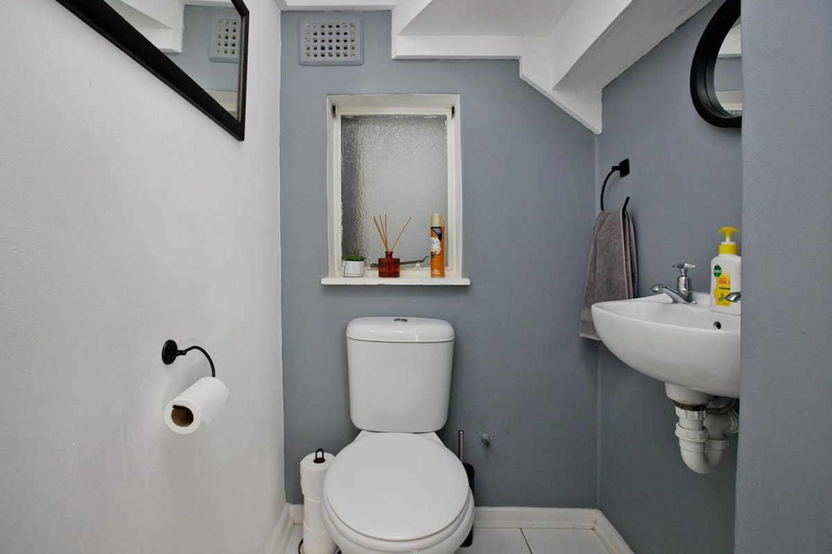A compact, well-maintained bathroom featuring a modern toilet, wall-mounted basin, and an obscured glass window for privacy.