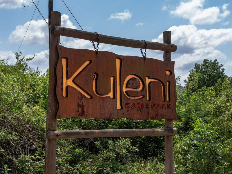 A rustic wooden and metal entrance sign for Kuleni Game Park, set against a natural bushveld backdrop.