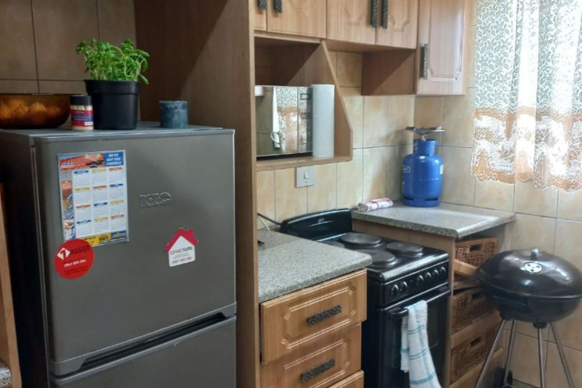 A compact kitchen featuring wooden cabinetry, tiled splashbacks, and a built-in stove with an oven.