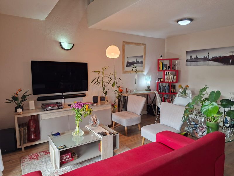 A well-maintained living room featuring laminate flooring and modern wall and ceiling lighting fixtures.