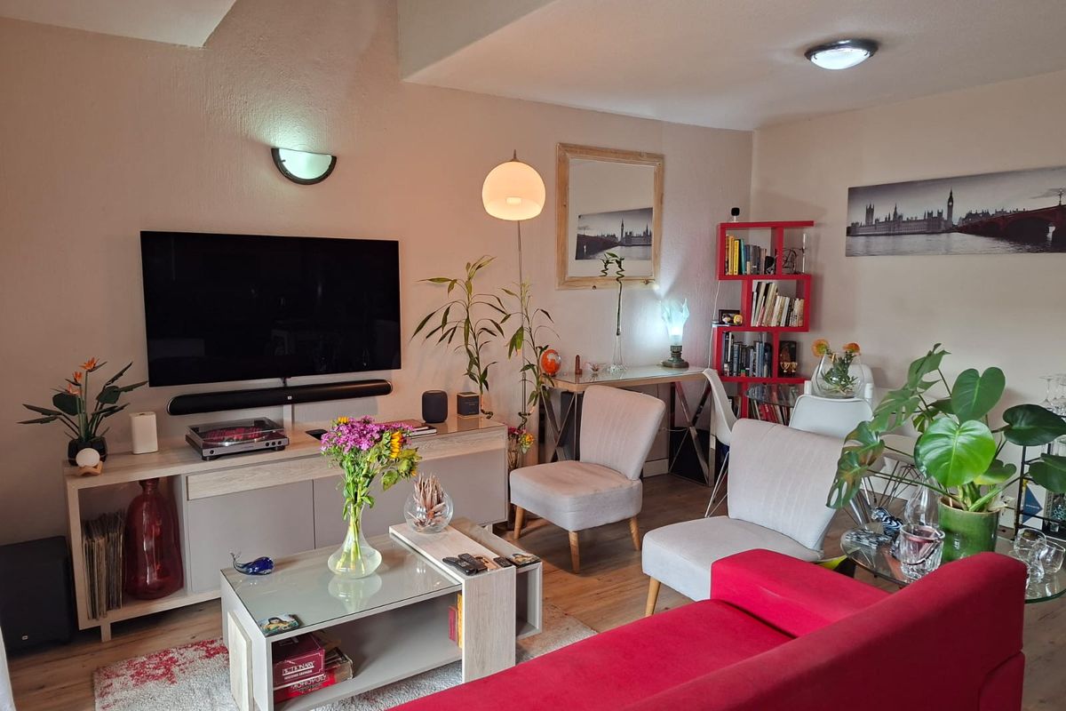 A well-maintained living room featuring laminate flooring and modern wall and ceiling lighting fixtures.