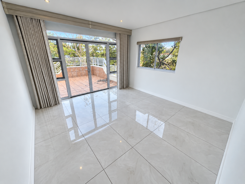 Bright and spacious living area featuring large format porcelain tiles, recessed lighting, and direct access to a private balcony through sliding glass doors.