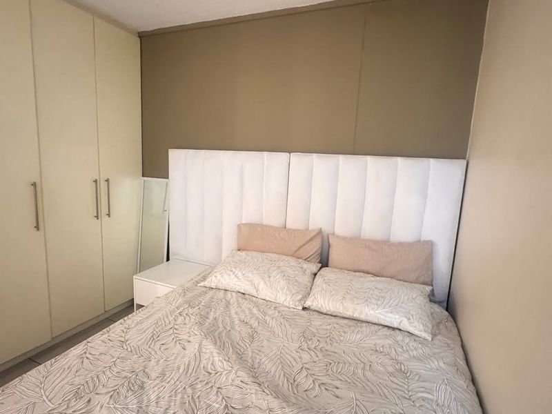 A compact bedroom featuring built-in cupboards and a neutral color palette, providing functional storage space.