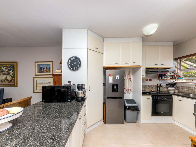A functional kitchen featuring granite countertops, built-in cabinetry, a built-in oven and hob, and tiled flooring with a neutral backsplash.