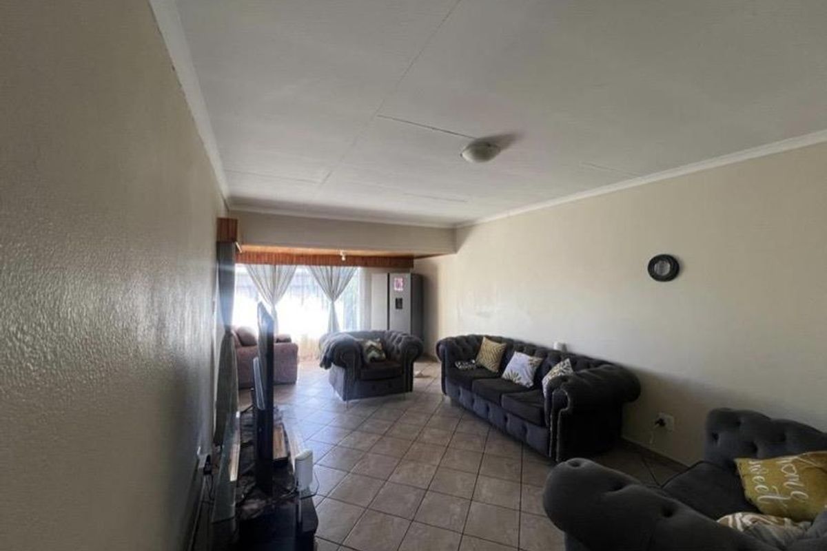 A spacious living room featuring tiled flooring and a coved ceiling, offering a functional layout for comfortable family living.