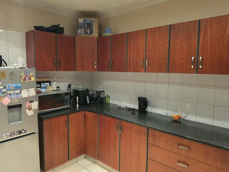 A functional kitchen featuring wood-look laminate cabinetry, dark granite countertops, and a neutral ceramic tile backsplash.