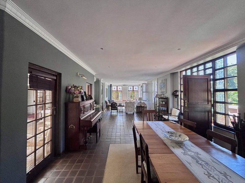 Spacious open-plan living and dining area featuring classic tiled flooring, elegant crown molding, and distinctive leaded glass windows providing ample natural light.