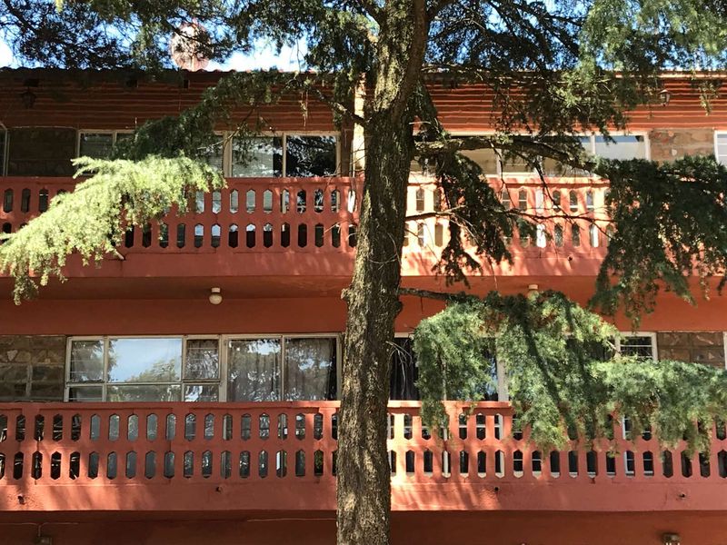 Exterior view of an apartment building featuring two levels of balconies with concrete balustrades and stone cladding facade details.