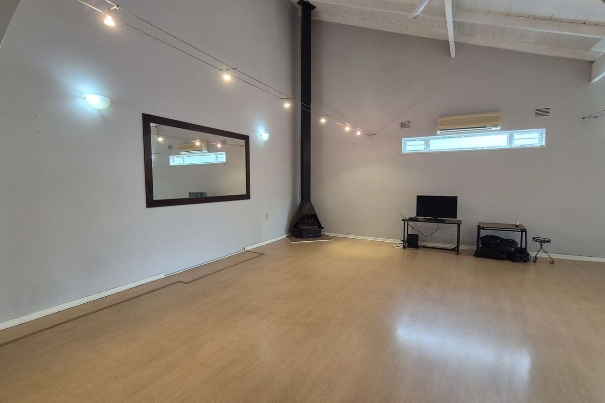 Spacious living area featuring high vaulted ceilings, a modern black freestanding fireplace, and light wood-look flooring, offering a bright and versatile open-plan layout.
