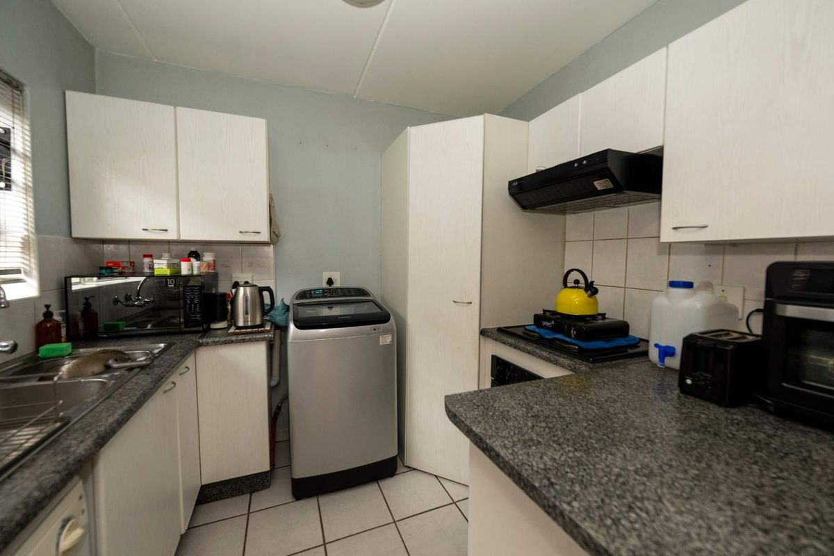 Compact kitchen featuring white cabinetry, granite-look countertops, tiled flooring, and a built-in extractor fan, providing a functional workspace.