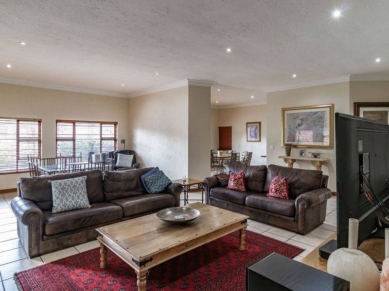 Spacious open-plan living area featuring tiled flooring, recessed downlighting, and large windows, creating a bright and versatile space for relaxation and dining.