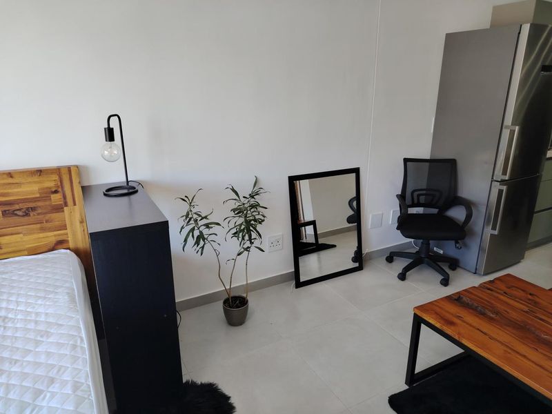 An open-plan living area featuring neutral tiled flooring and clean white walls, providing a versatile space for combined living and sleeping arrangements.