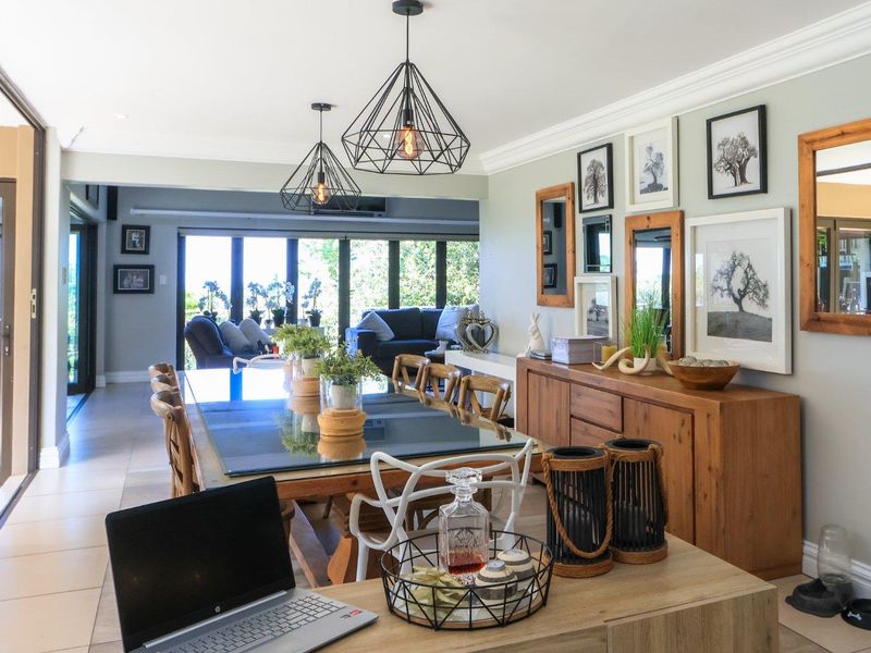 Spacious open-plan dining and living area featuring tiled floors, modern pendant lighting, and large sliding glass doors leading to an outdoor patio.