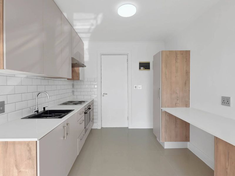 Modern, clean-lined kitchen featuring neutral cabinetry, subway tile backsplash, integrated appliances, and a functional breakfast bar area with tiled flooring.