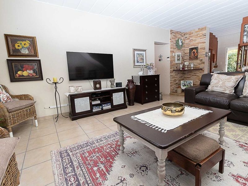 A comfortable living room featuring tiled flooring, a stone accent wall, and a classic tongue and groove ceiling.