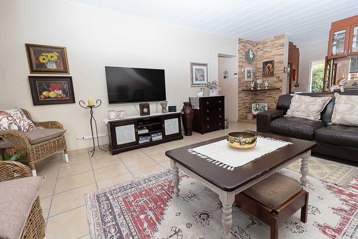 A comfortable living room featuring tiled flooring, a stone accent wall, and a classic tongue and groove ceiling.