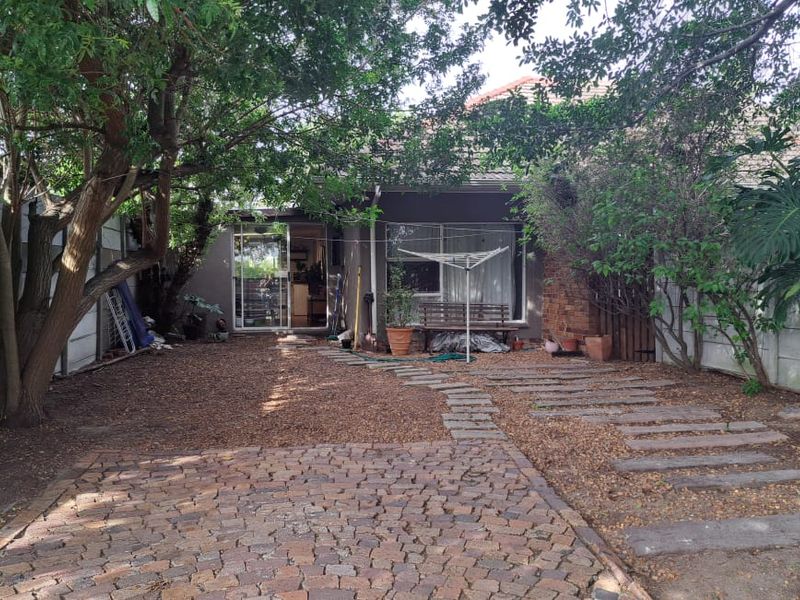 Rear garden area featuring brick paving, concrete stepping stones, and a precast boundary wall, providing access to the cottage via a sliding glass door.
