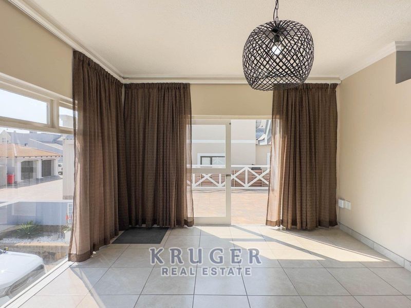 Bright and spacious living area featuring large windows, tiled flooring, and direct access to an outdoor patio area.