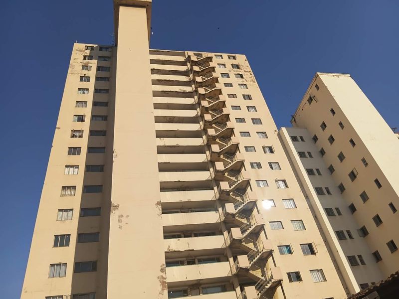 Low-angle view of a high-rise apartment building facade featuring an external fire escape staircase and visible signs of exterior wear.