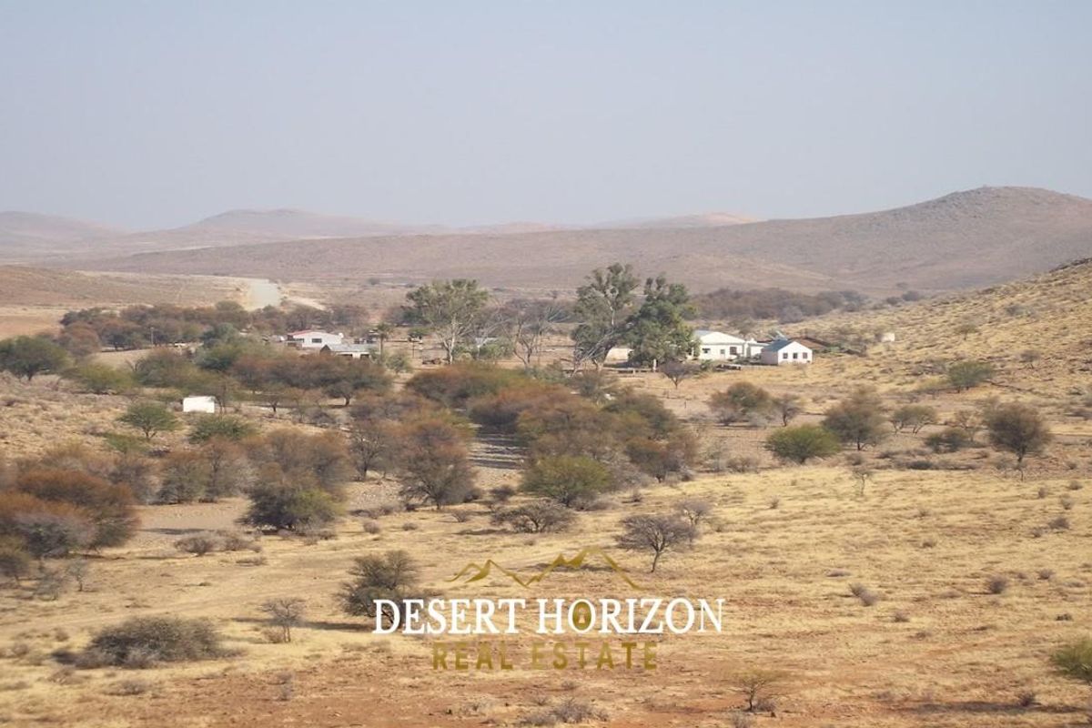 A wide-angle aerial view of the farm property, showcasing the main dwelling and surrounding arid landscape.