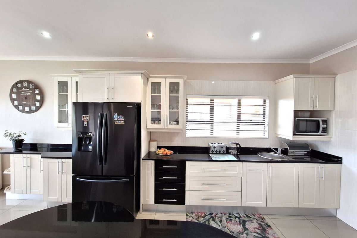 Modern kitchen featuring white cabinetry, contrasting black countertops, recessed lighting, and a built-in microwave, offering a clean and functional culinary space.