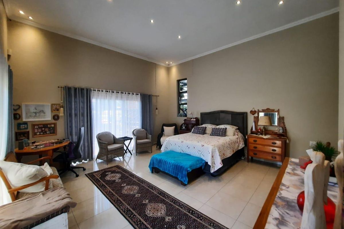 Spacious bedroom featuring high ceilings, tiled flooring, recessed downlighting, and large sliding glass doors providing access to the exterior.