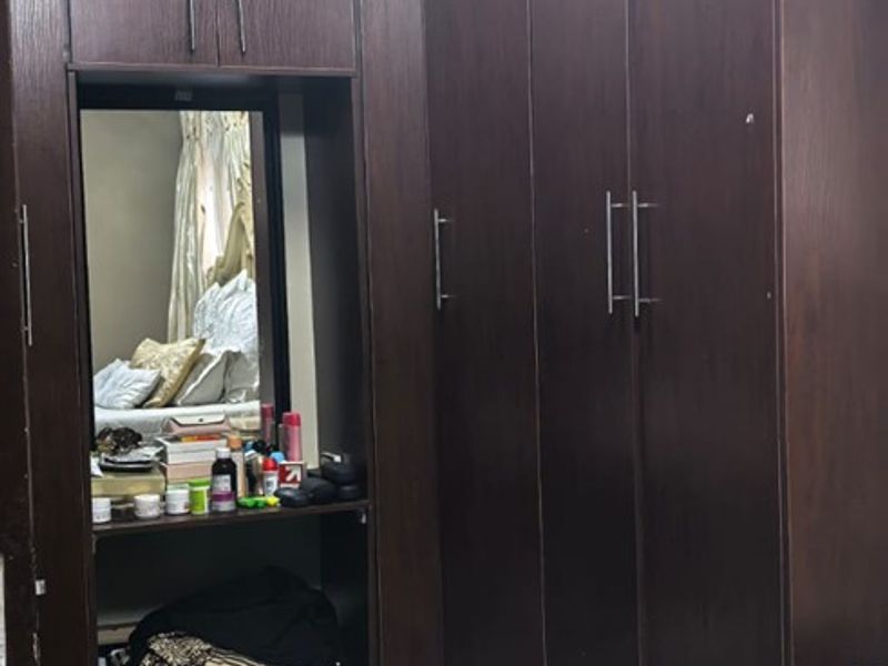 Bedroom featuring dark wood built-in cupboards with an integrated vanity mirror and overhead lighting.