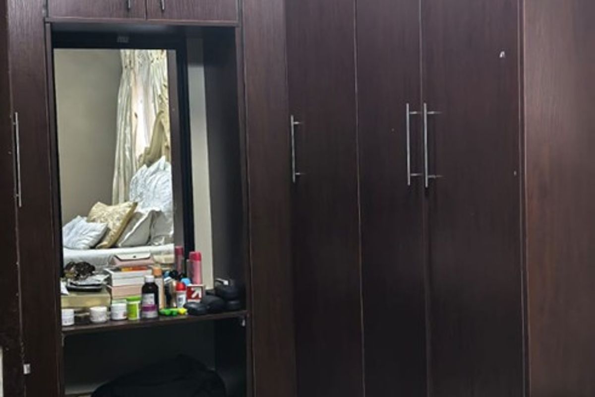 Bedroom featuring dark wood built-in cupboards with an integrated vanity mirror and overhead lighting.