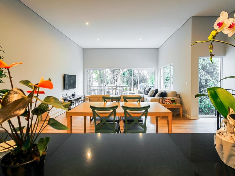 Spacious open-plan living and dining area featuring modern recessed lighting, hardwood flooring, and large sliding glass doors leading to an outdoor space.