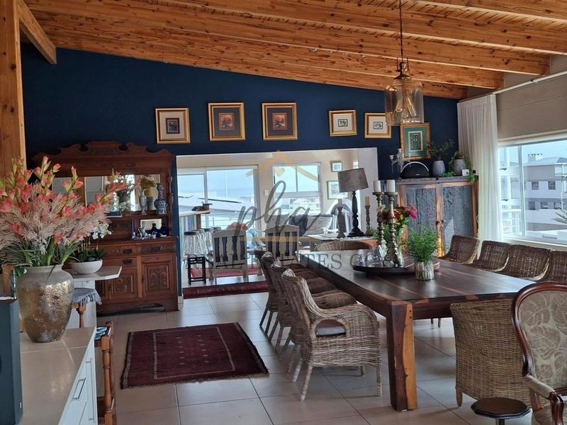 Spacious dining area featuring exposed timber ceiling beams, tiled flooring, and large windows providing ample natural light.