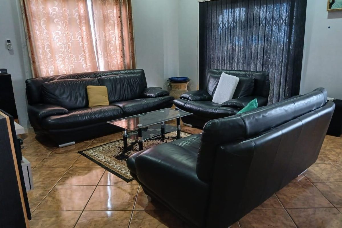 A living room featuring tiled flooring and a sliding door with a security gate, providing access to the exterior.