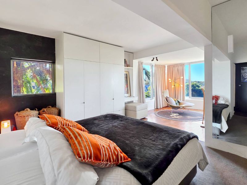 Spacious bedroom featuring extensive built-in cabinetry, a large full-length mirror, and expansive windows providing natural light and scenic views.