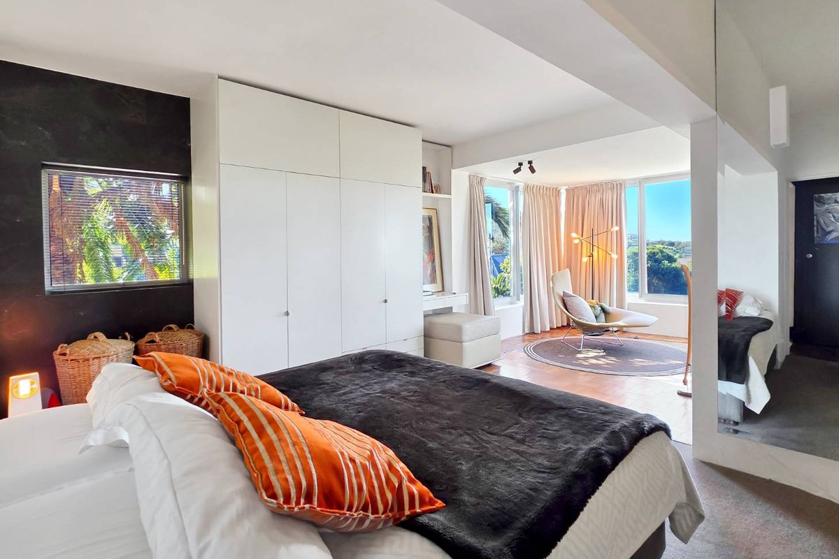 Spacious bedroom featuring extensive built-in cabinetry, a large full-length mirror, and expansive windows providing natural light and scenic views.