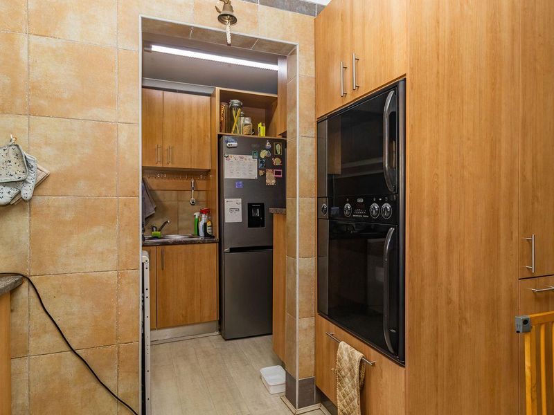 A functional scullery area featuring built-in cabinetry, a stainless steel sink, and integrated oven, providing additional prep and storage space adjacent to the main kitchen.