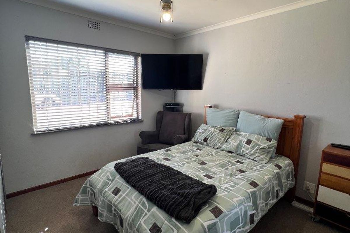 A functional bedroom featuring a ceiling fan, carpeted flooring, and a window with fitted blinds.