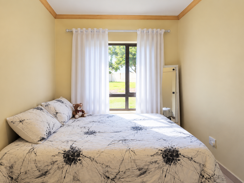 A cozy bedroom featuring neutral walls, timber crown molding, and a large window that allows for natural light.