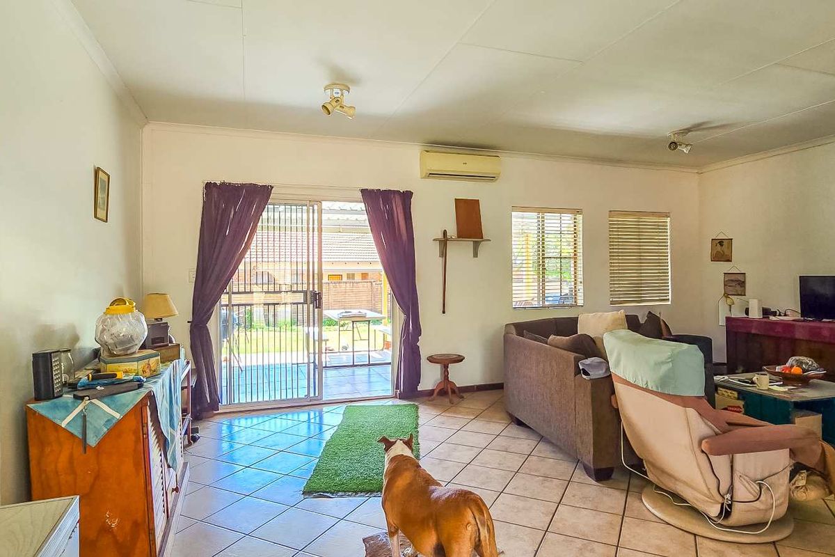 Spacious living room featuring tiled flooring, a split-system air conditioner, and sliding glass doors providing direct access to the outdoor area.
