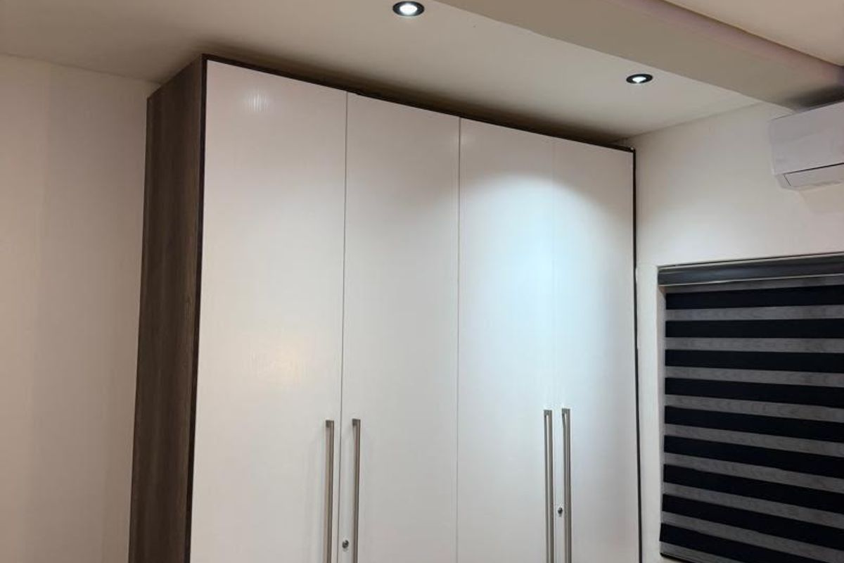 A well-maintained bedroom featuring a modern built-in wardrobe, recessed ceiling lighting, and a wall-mounted split-system air conditioning unit.