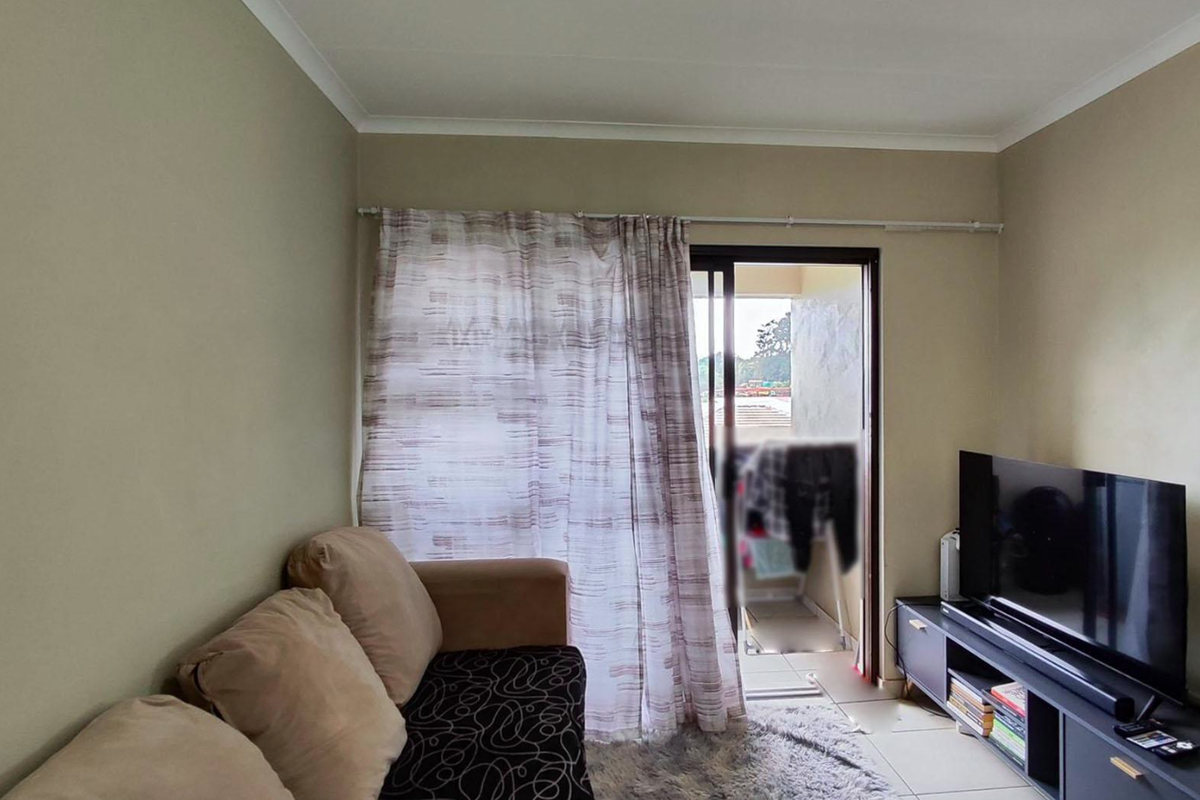 A living room featuring tiled flooring and a sliding glass door providing access to an outdoor balcony area.