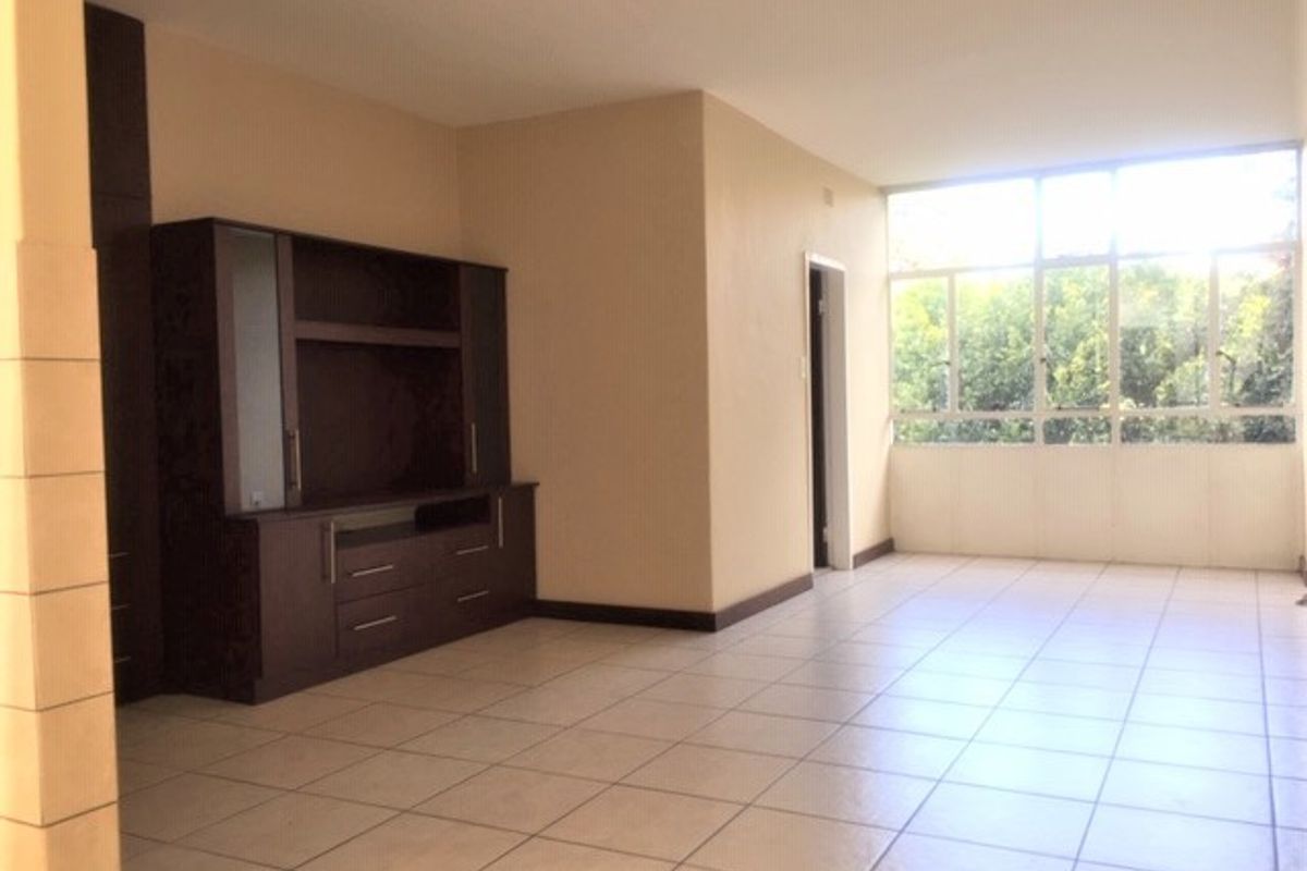 Spacious living area featuring neutral tiled flooring, large windows providing natural light, and built-in cabinetry for storage.